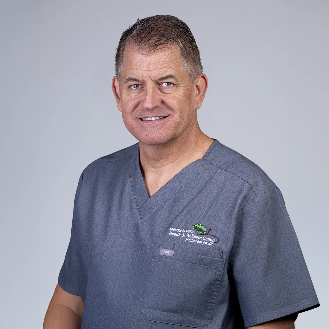 Person in medical scrubs, neutral background.