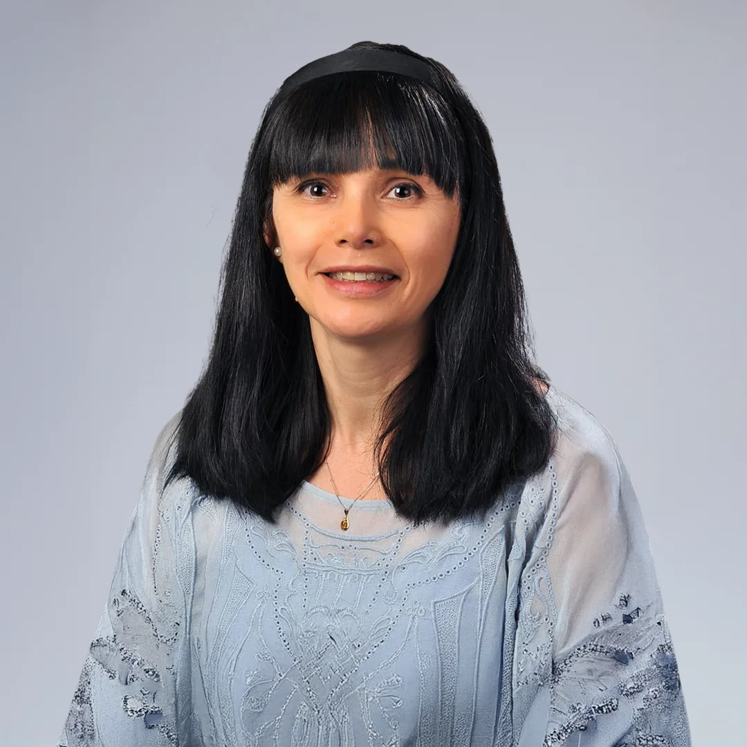Woman in blue top, neutral background.