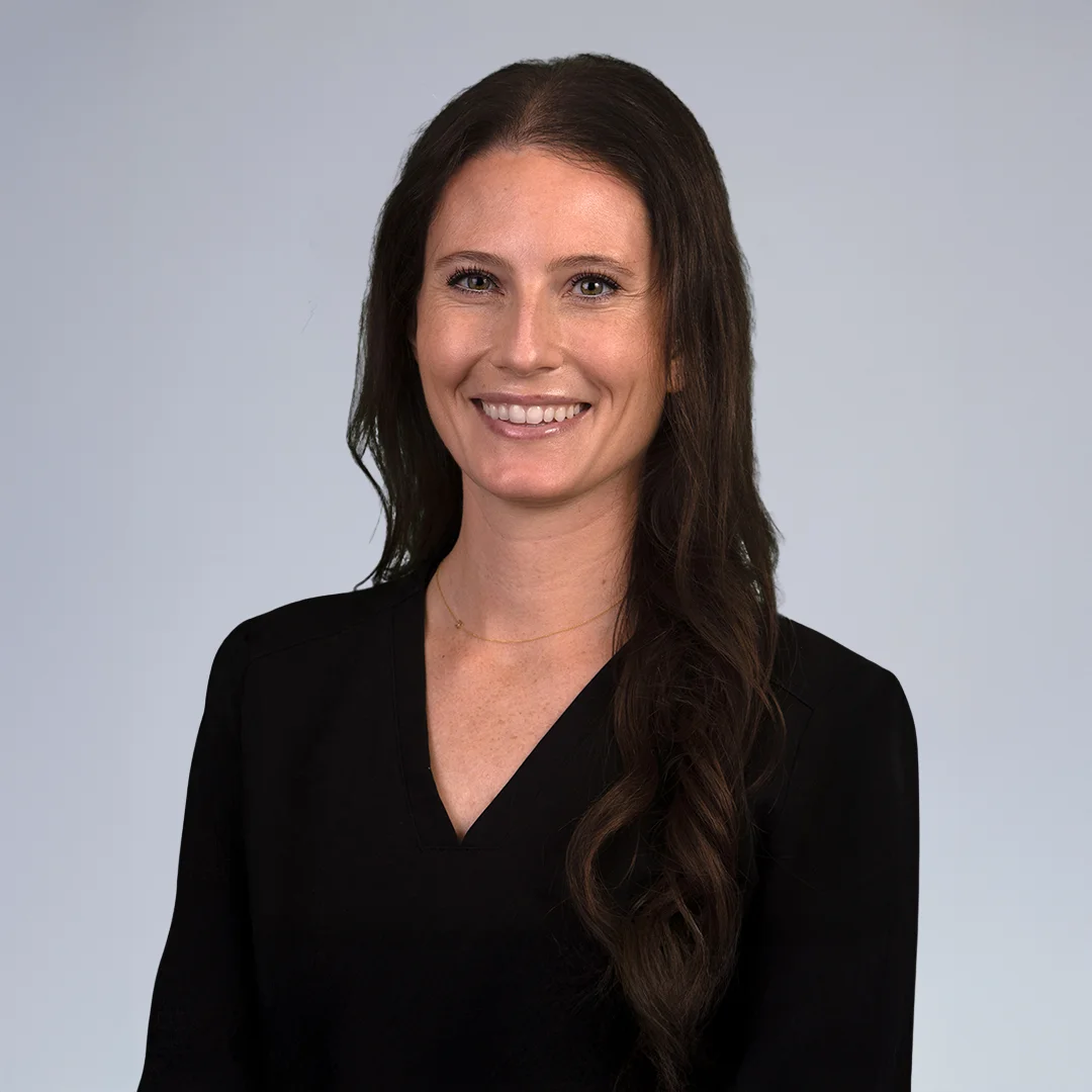 Person in black top, neutral background.