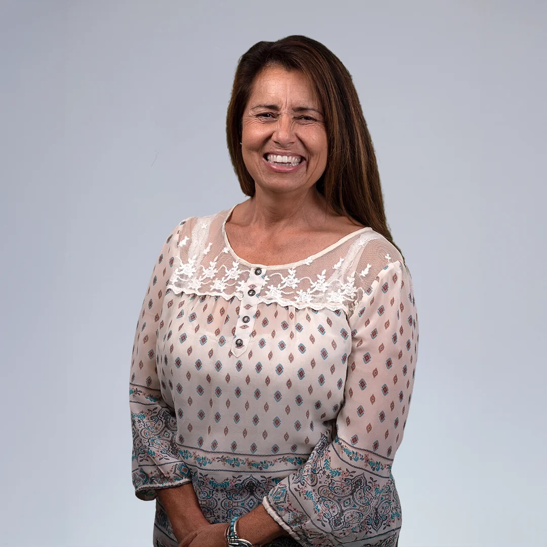 Woman in patterned blouse, neutral background.