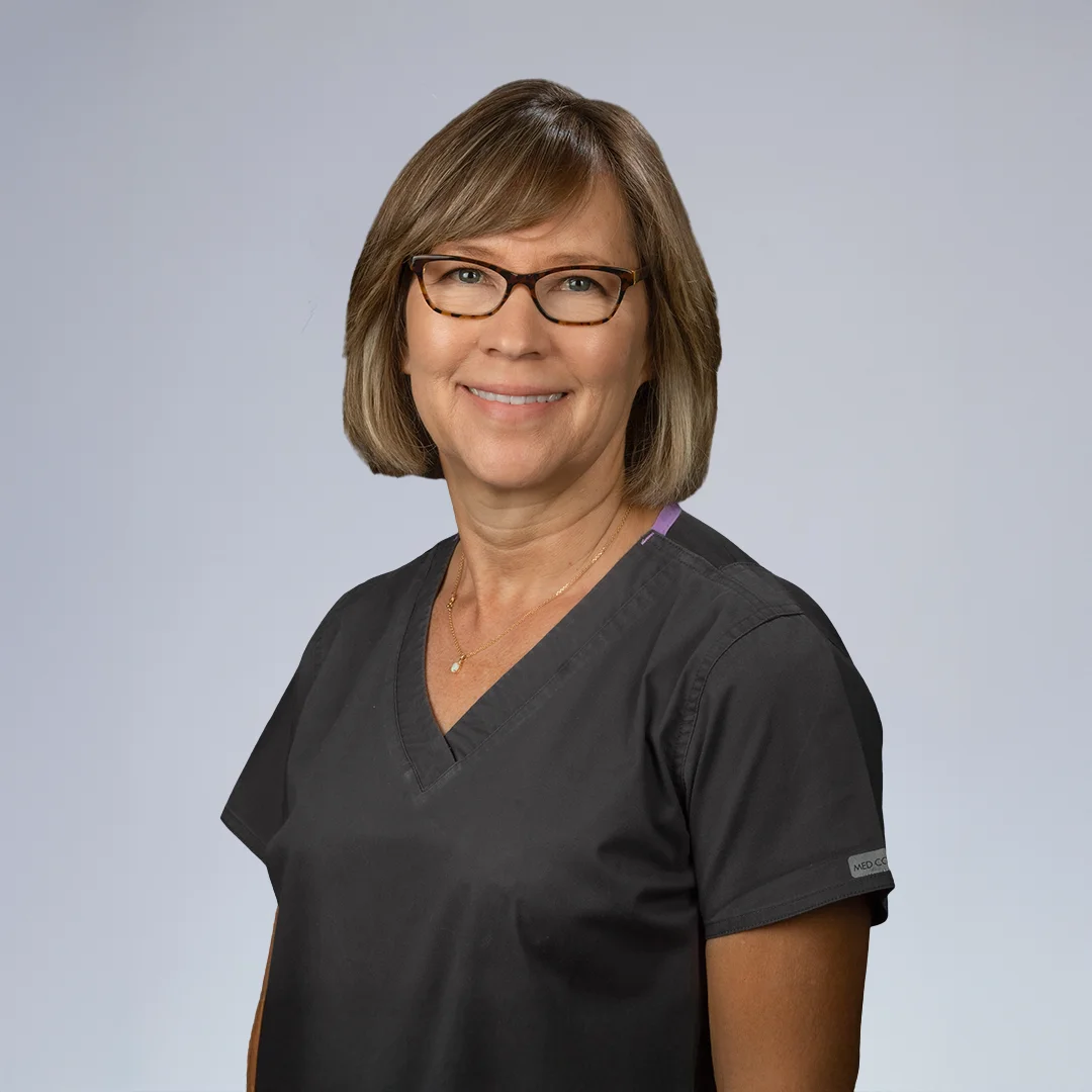 Person in medical scrubs, neutral background.