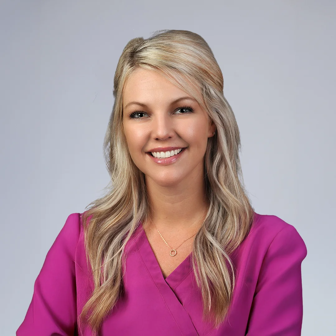 Woman in purple blouse, neutral background.