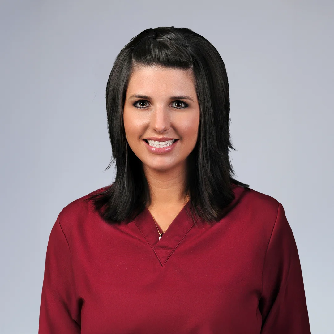 Person in maroon scrubs, neutral background.