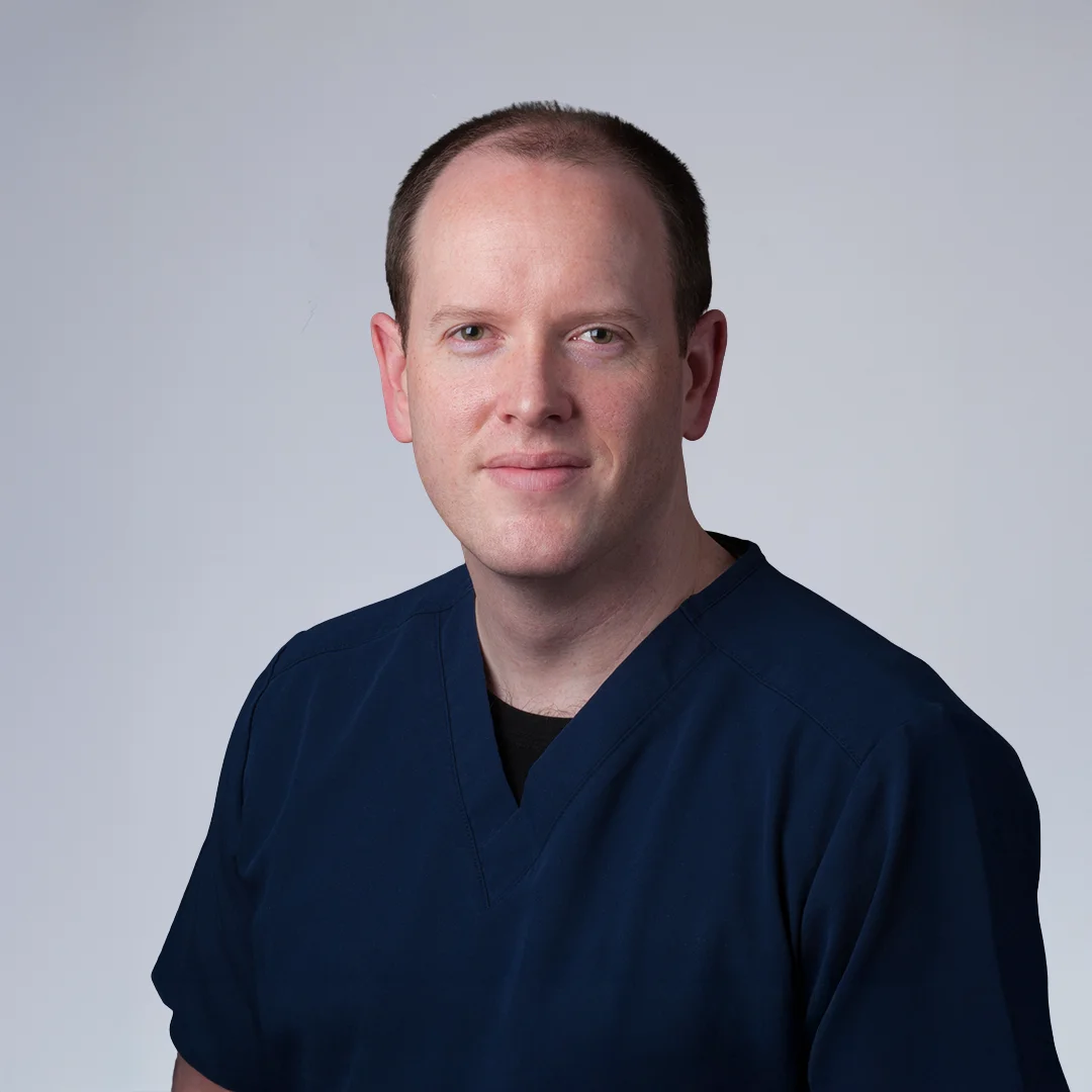 Person in medical scrubs, neutral background.