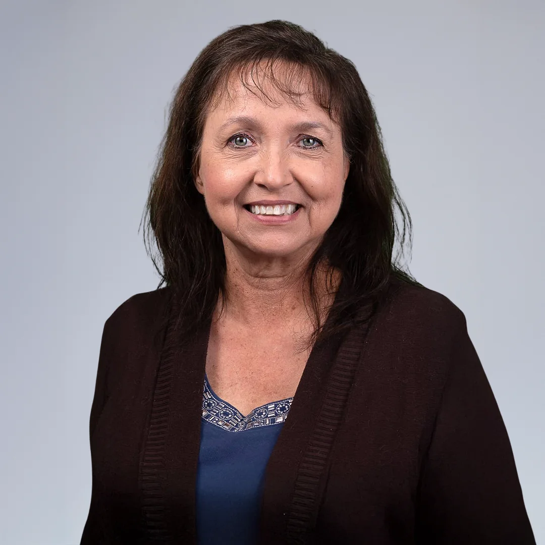 Woman in dark cardigan, neutral background.