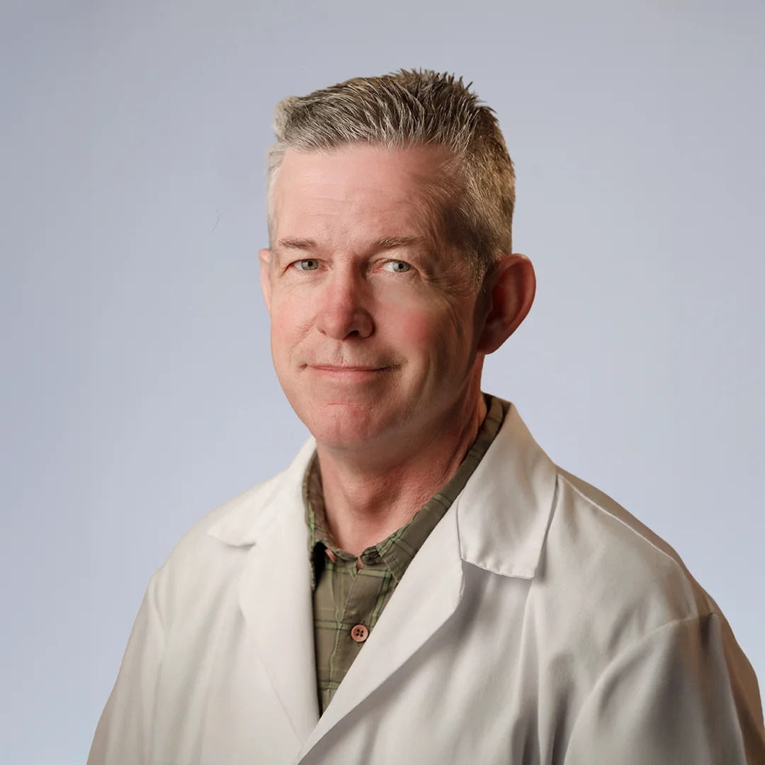 Man in lab coat, neutral background.