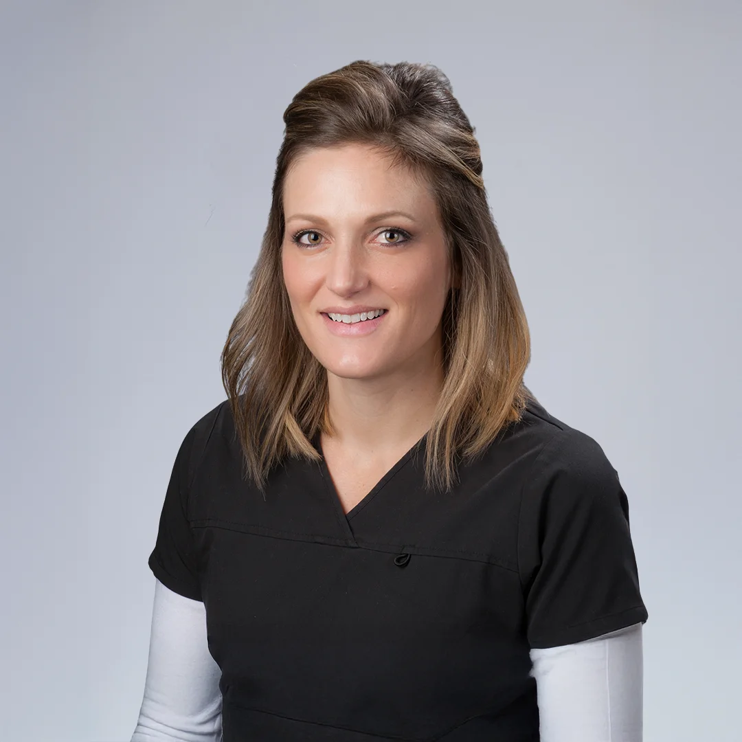 Person in medical attire, neutral background.